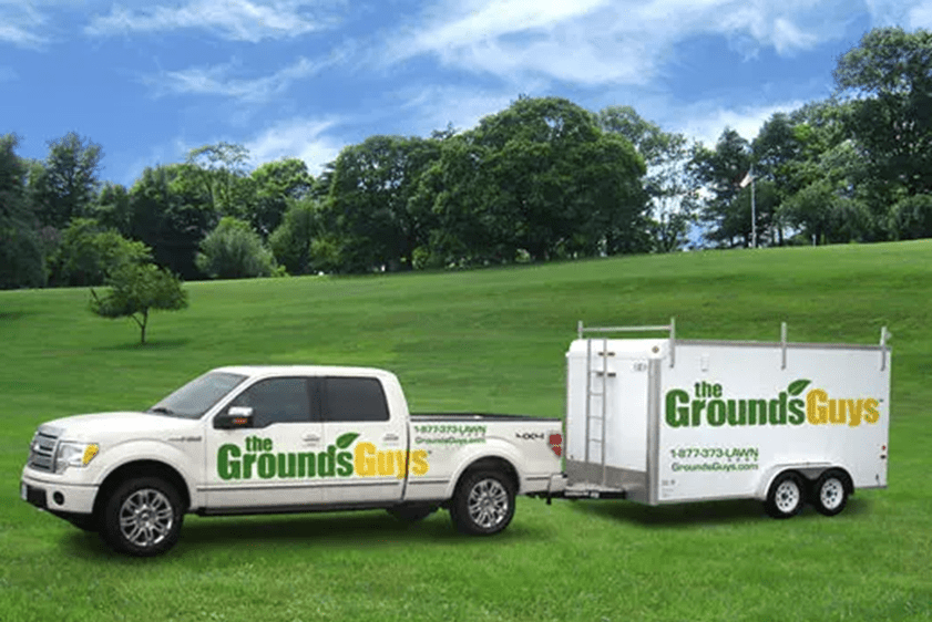 Outside view of truck with trailer with the Grounds Guys graphics.