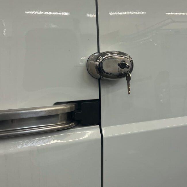 Exterior view of a Lock Dog installed on a cargo van with a key hanging in the lock.