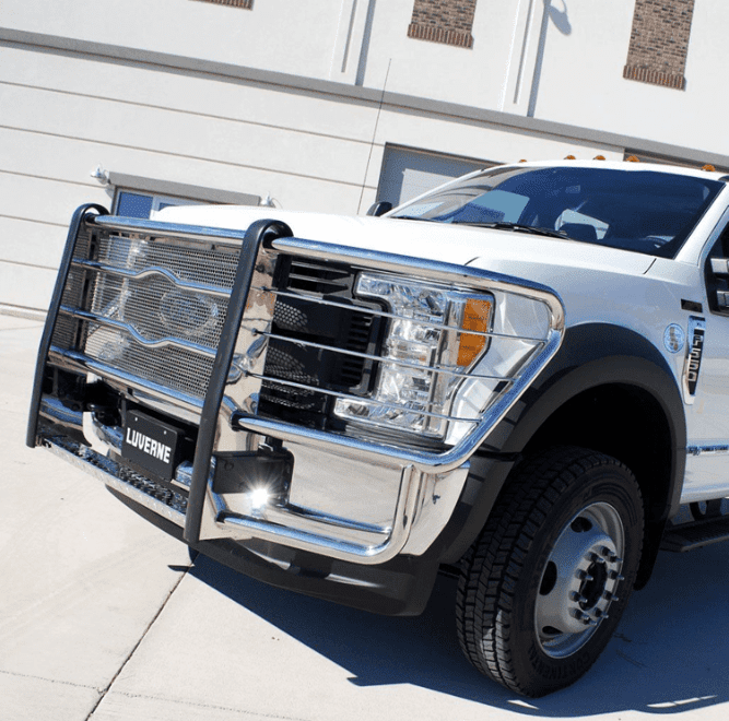 View of front of a white truck with an attached chrome grill.